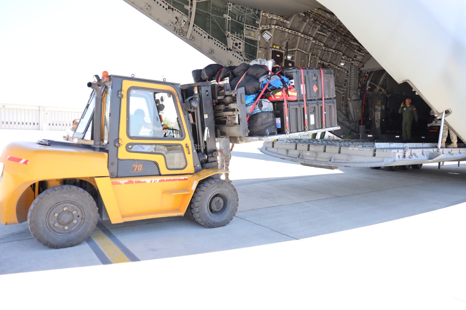 Askeri kargo uçağına forklift ile insani yardım malzemeleri ve ekipman yükleniyor.