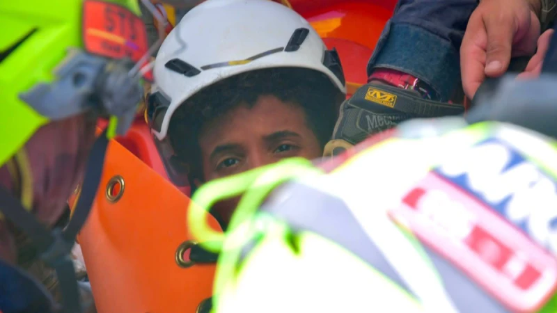 Venezuela depreminde enkazdan 70 saat sonra kurtarılan 11 yaşındaki Moises, beyaz baretli olarak sedyede, etrafında kurtarma ekipleri çalışırken görülüyor.